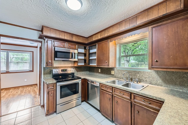 kitchen featuring backsplash, crown molding, stainless steel appliances, and a sink
