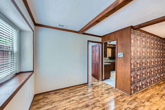 interior space featuring ornamental molding, visible vents, a textured ceiling, and wood finished floors