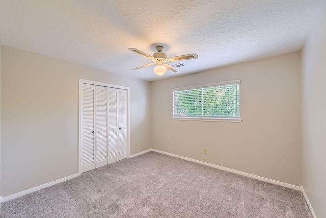 unfurnished bedroom featuring a textured ceiling, a closet, visible vents, and carpet floors
