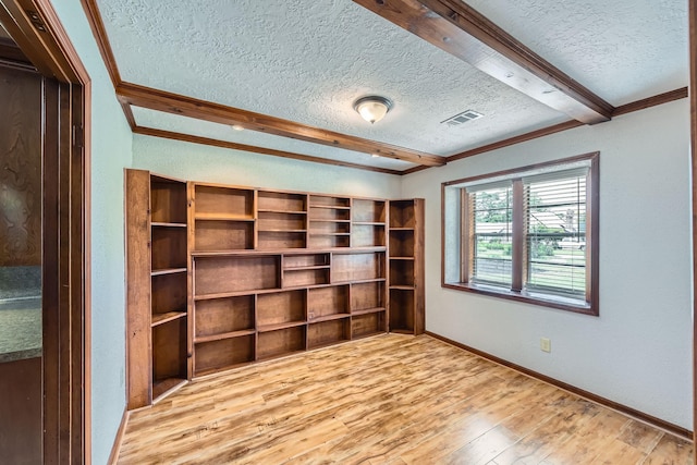 empty room with a textured ceiling, baseboards, visible vents, and wood finished floors