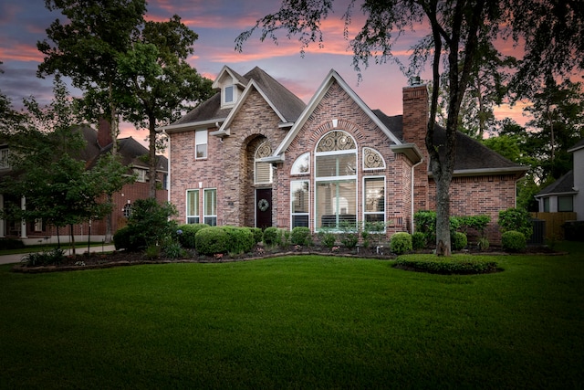 view of front of property with a front lawn, brick siding, a chimney, and cooling unit