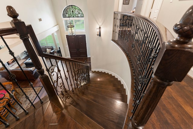 staircase with baseboards, a high ceiling, and wood finished floors