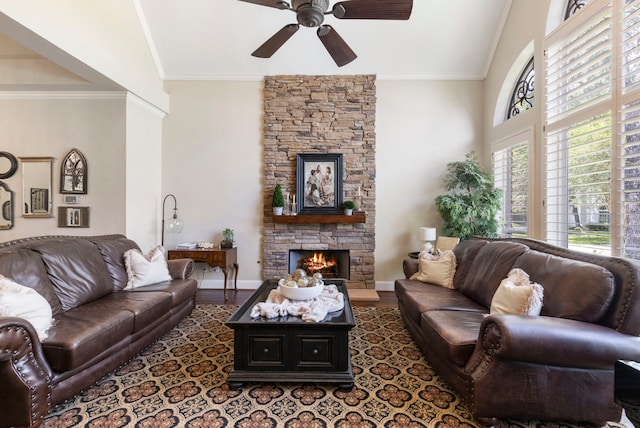 living room featuring baseboards, ceiling fan, crown molding, wood finished floors, and a fireplace