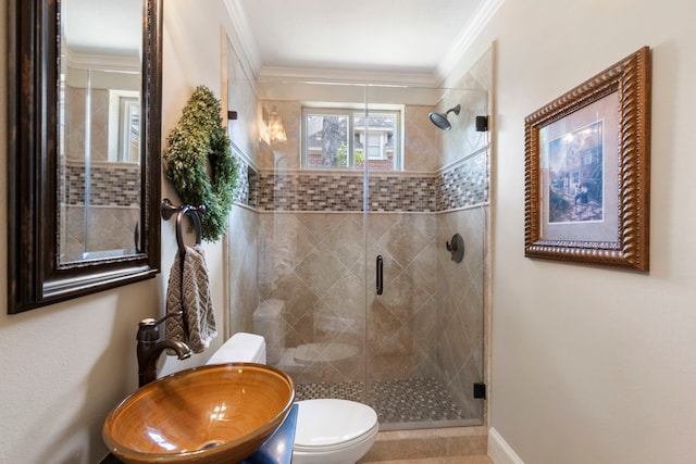 full bath with a sink, crown molding, toilet, and a stall shower