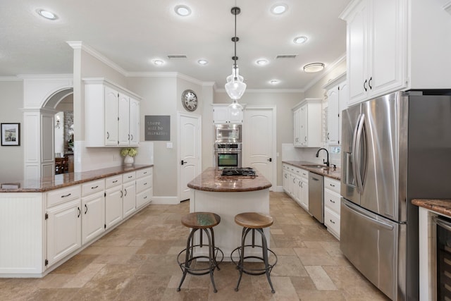kitchen with stone tile floors, white cabinetry, a kitchen island, backsplash, and stainless steel appliances