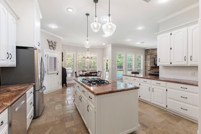 kitchen featuring appliances with stainless steel finishes, ornamental molding, a kitchen island, and stone tile flooring