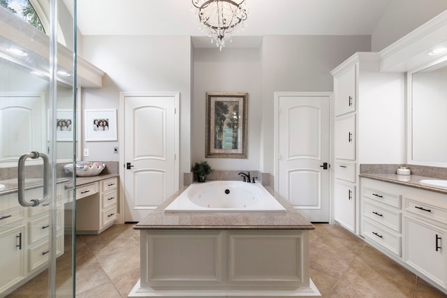 bathroom featuring a notable chandelier, a jetted tub, vanity, and tile patterned floors
