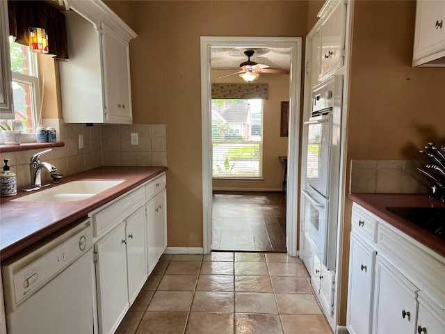 kitchen featuring a ceiling fan, white appliances, a sink, decorative backsplash, and white cabinets