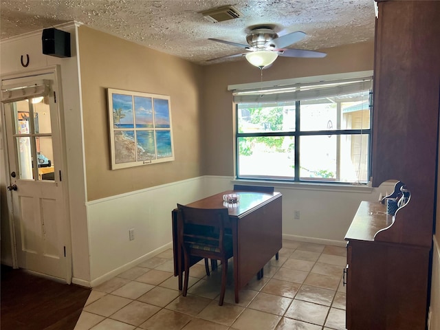 dining area with a textured ceiling, visible vents, baseboards, ceiling fan, and light tile patterned flooring