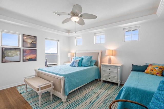 650 Dove Is, Livingston, TX 77351 - bedroom featuring baseboards, multiple windows, a tray ceiling, and wood finished floors