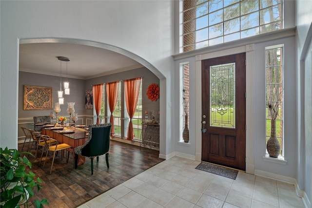 foyer entrance featuring arched walkways, ornamental molding, and tile patterned floors