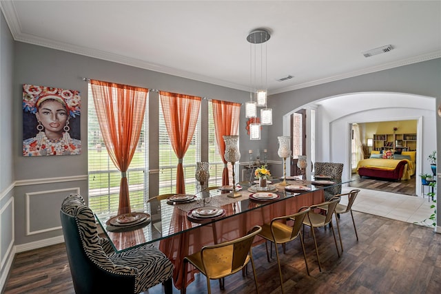 dining room with ornamental molding, visible vents, wood finished floors, and arched walkways