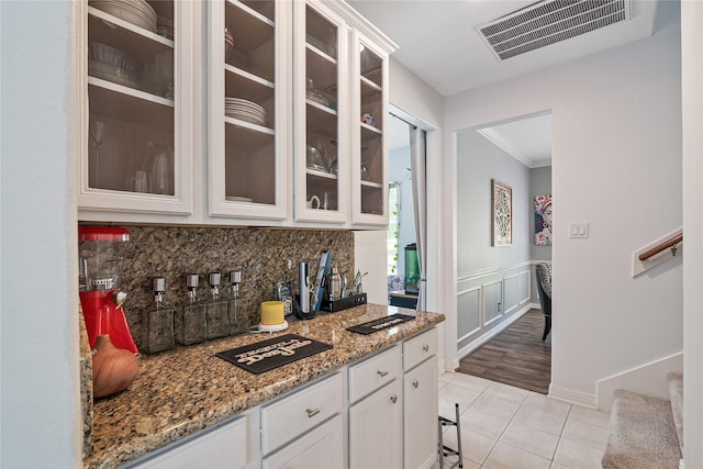 kitchen with tasteful backsplash, light tile patterned flooring, visible vents, crown molding, and white cabinetry