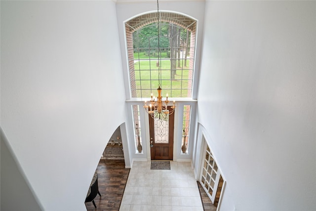 foyer entrance with arched walkways, baseboards, a chandelier, and a towering ceiling
