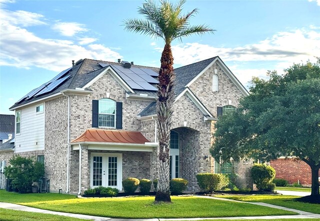 3103 Lenora Springs Dr, Spring, TX 77386 - french country style house featuring french doors, a front lawn, brick siding, and solar panels