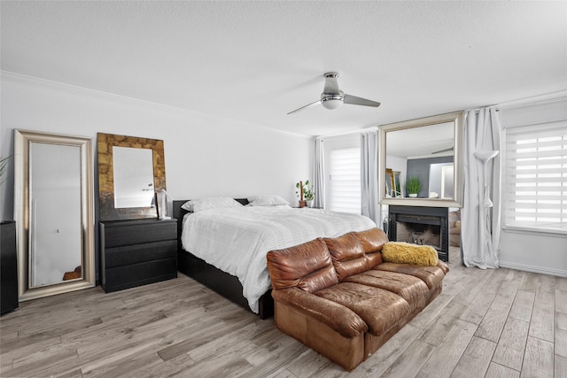 9850 Pagewood Ln Unit 1302, Houston, TX 77042 - bedroom featuring a fireplace, a ceiling fan, and wood finished floors