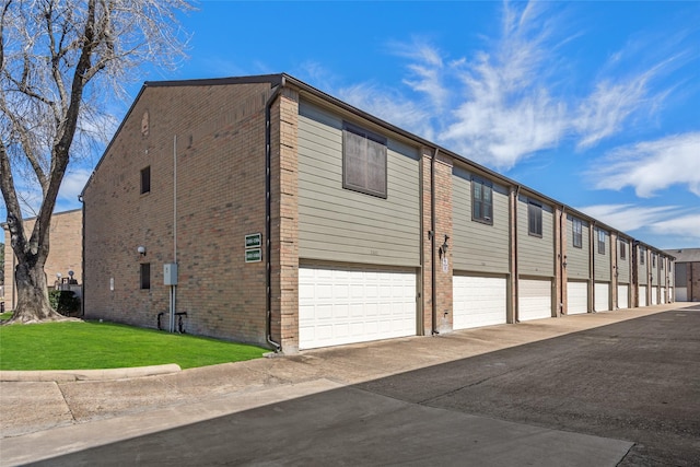9850 Pagewood Ln Unit 1302, Houston, TX 77042 - view of home's exterior with a yard, driveway, brick siding, and an attached garage