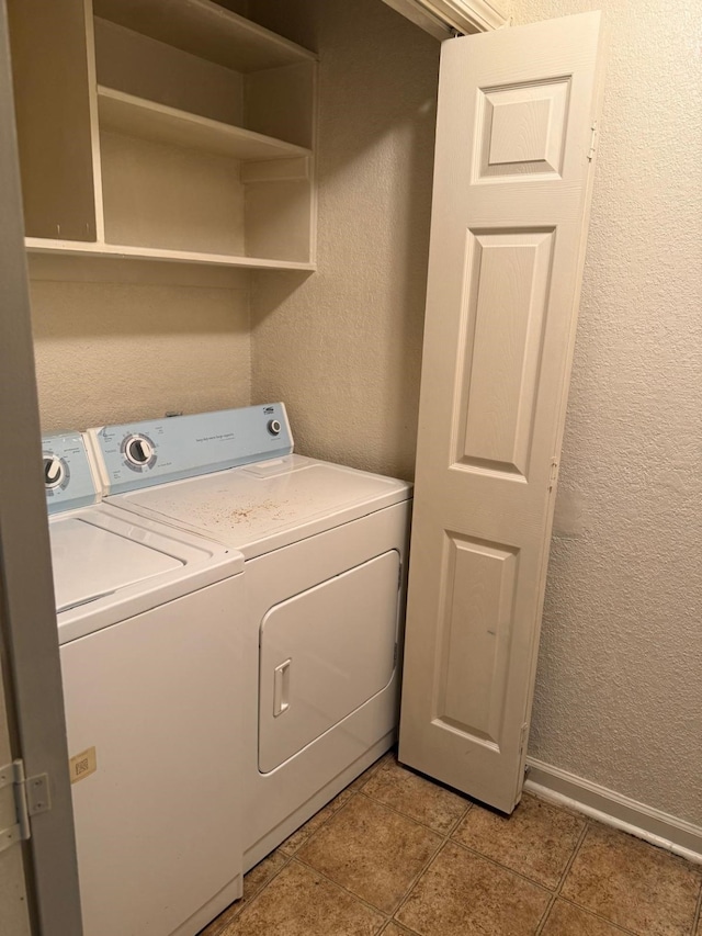 laundry area with laundry area, light tile patterned flooring, a textured wall, and baseboards