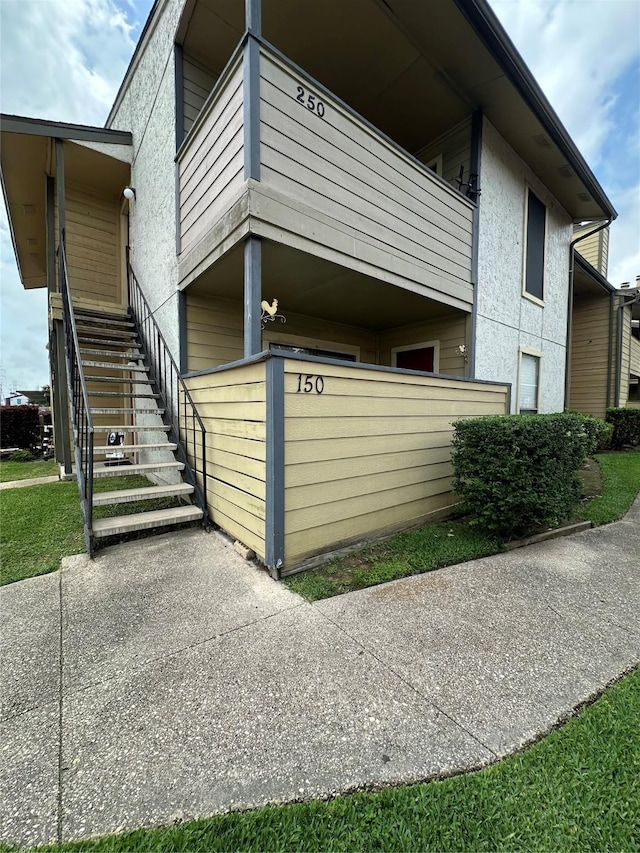 view of home's exterior with a balcony, stairs, and stucco siding