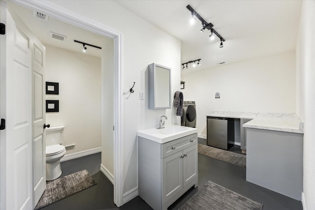 1210 Persimmon Pass, Fischer, TX 78623 - bathroom with track lighting, independent washer and dryer, finished concrete floors, toilet, and baseboards