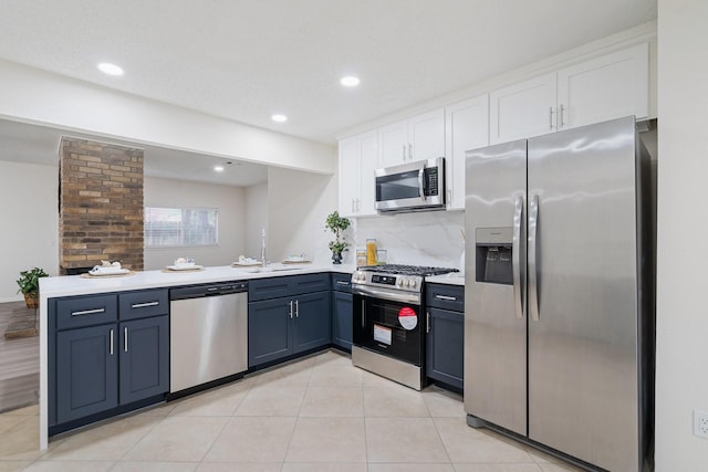 34 Quiet Peace Pl, The Woodlands, TX 77381 - kitchen with stainless steel appliances, a sink, white cabinets, a peninsula, and light countertops