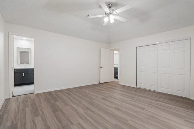 34 Quiet Peace Pl, The Woodlands, TX 77381 - unfurnished bedroom with light wood-type flooring, a sink, a closet, ensuite bath, and baseboards