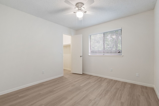 34 Quiet Peace Pl, The Woodlands, TX 77381 - spare room with light wood finished floors, ceiling fan, baseboards, and a textured ceiling