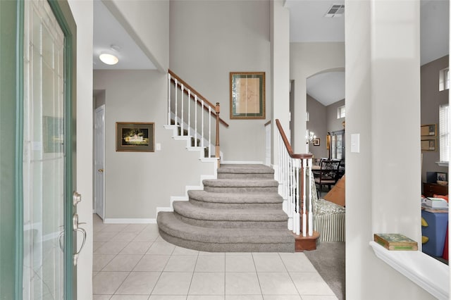 22 Almond Branch Pl, The Woodlands, TX 77382 - foyer featuring arched walkways, a towering ceiling, stairs, light tile patterned floors, and baseboards