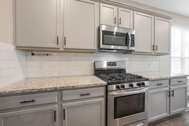 16129 Barge Way, Crosby, TX 77532 - kitchen with stainless steel appliances, gray cabinetry, decorative backsplash, and light stone counters
