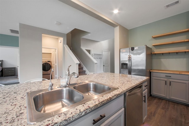 16129 Barge Way, Crosby, TX 77532 - kitchen with stainless steel appliances, gray cabinets, a sink, washing machine and dryer, and dark wood-type flooring