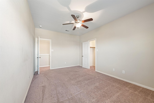 unfurnished bedroom featuring carpet flooring, baseboards, a spacious closet, and a ceiling fan