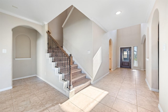 entryway featuring arched walkways, crown molding, stairs, baseboards, and light tile patterned floors