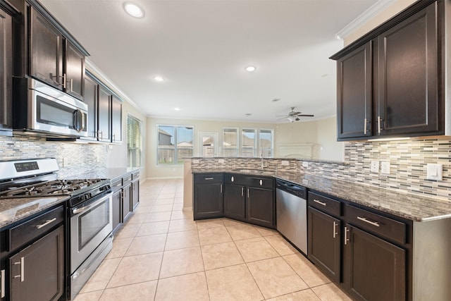 kitchen with stainless steel appliances, a sink, a ceiling fan, dark stone countertops, and recessed lighting