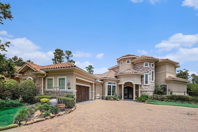 2802 Twin Fountains Dr, Houston, TX 77068 - mediterranean / spanish house featuring stone siding, stucco siding, a garage, and decorative driveway