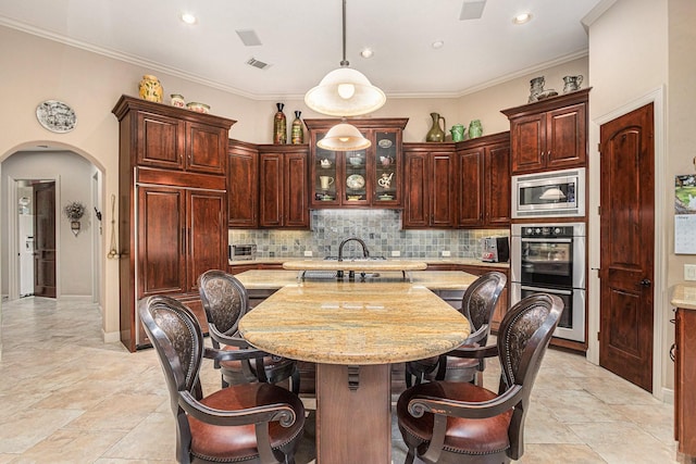 2802 Twin Fountains Dr, Houston, TX 77068 - kitchen featuring stainless steel appliances, arched walkways, decorative light fixtures, a center island, and decorative backsplash