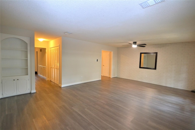 14459 Misty Meadow Ln, Houston, TX 77079 - unfurnished living room with dark wood-style floors, brick wall, a ceiling fan, baseboards, and a textured ceiling