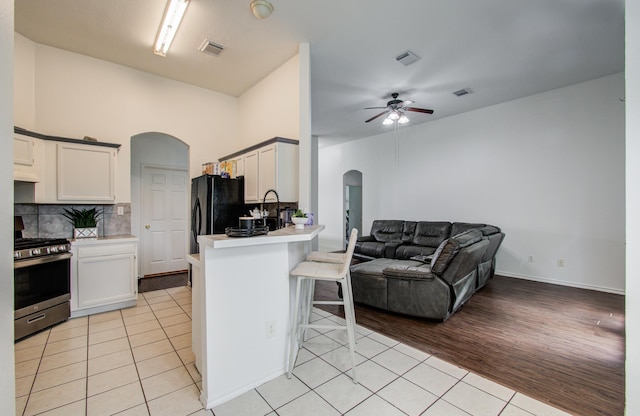 3116 Grassmere St, Houston, TX 77051 - kitchen with arched walkways, gas stove, freestanding refrigerator, light tile patterned flooring, and ceiling fan