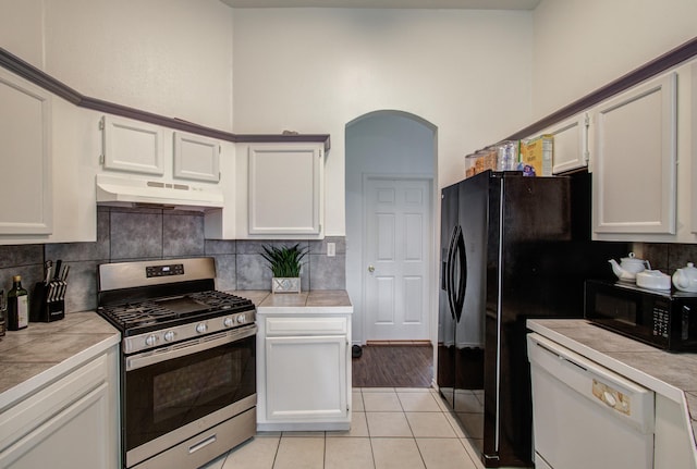 3116 Grassmere St, Houston, TX 77051 - kitchen featuring black appliances, under cabinet range hood, tile counters, backsplash, and white cabinetry