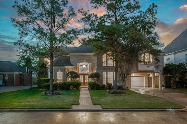 view of front facade with french doors, concrete driveway, an attached garage, and a lawn