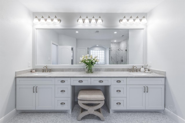 full bath with a marble finish shower, double vanity, and baseboards
