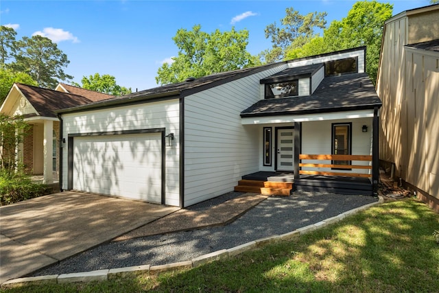 view of front of property featuring a garage, covered porch, driveway, and a shingled roof