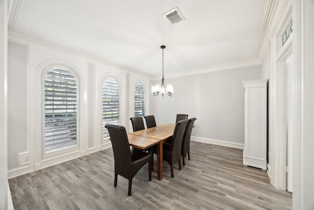 dining area featuring crown molding, wood finished floors, a chandelier, and baseboards