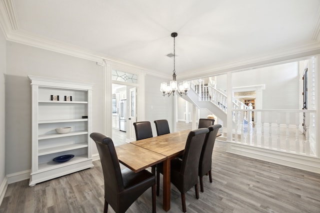 dining area featuring a chandelier, wood finished floors, stairs, ornamental molding, and baseboards