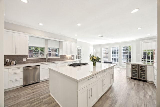 kitchen featuring appliances with stainless steel finishes, a sink, crown molding, recessed lighting, and plenty of natural light