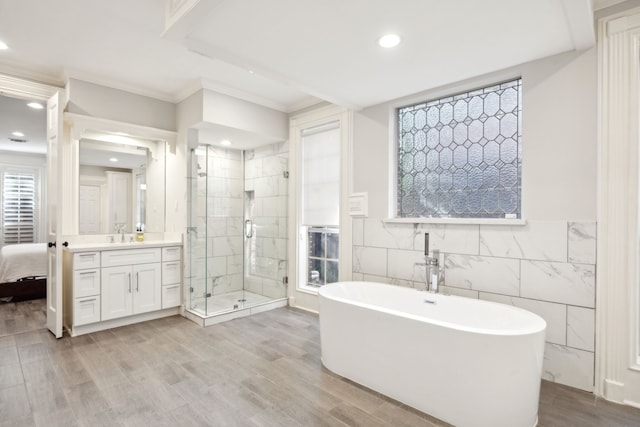 ensuite bathroom featuring a stall shower, tile walls, recessed lighting, vanity, and a soaking tub