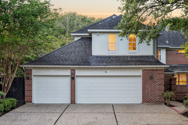 garage at dusk featuring concrete driveway
