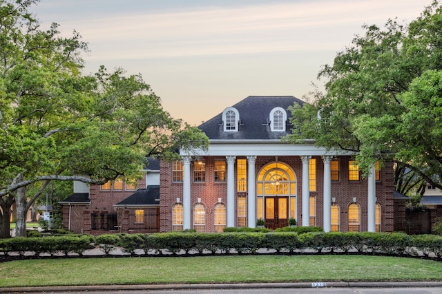 greek revival house featuring brick siding and a front yard