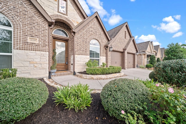 28209 Regal Wood Ct, Spring, TX 77386 - view of exterior entry with brick siding, a garage, driveway, and stone siding