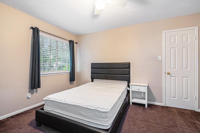 bedroom featuring dark carpet, baseboards, a ceiling fan, and a textured ceiling