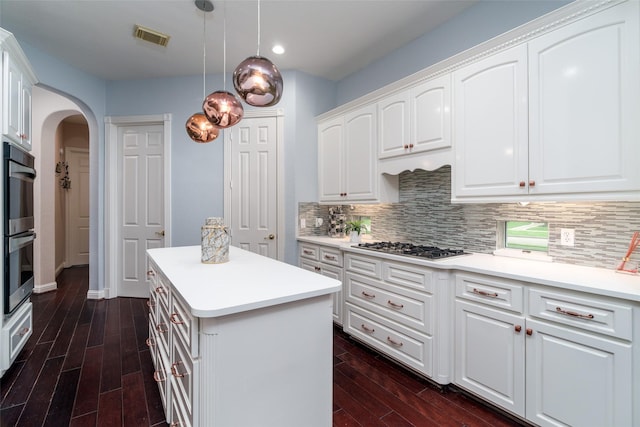 2130 White Eagle Ln, Katy, TX 77450 - kitchen featuring arched walkways, appliances with stainless steel finishes, dark wood finished floors, a kitchen island, and backsplash